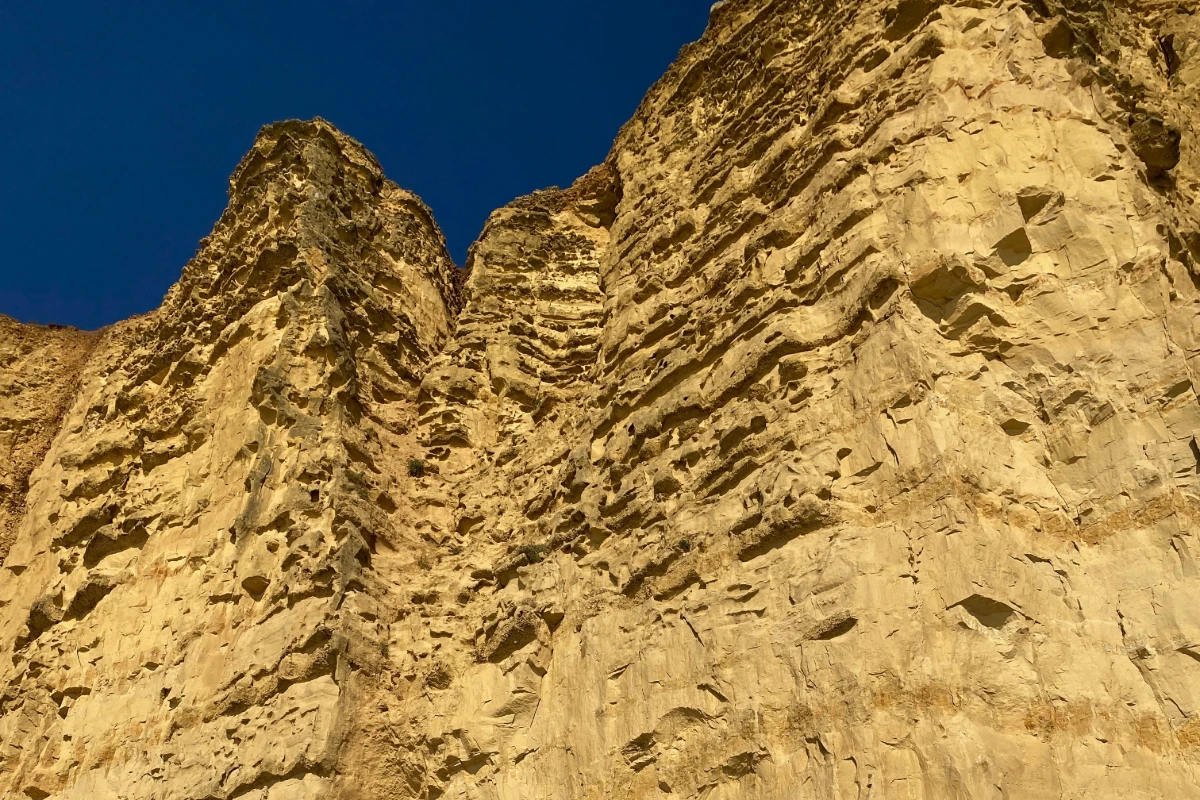 Steep golden rock strata rising against a deep blue sky